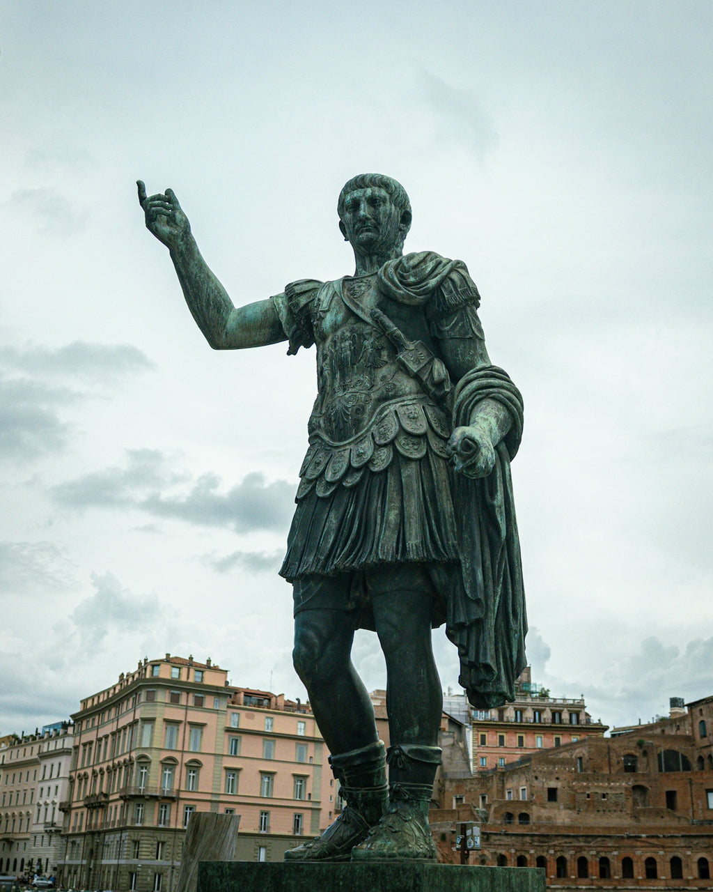 Bronze statue of a roman emperor in front of buildings