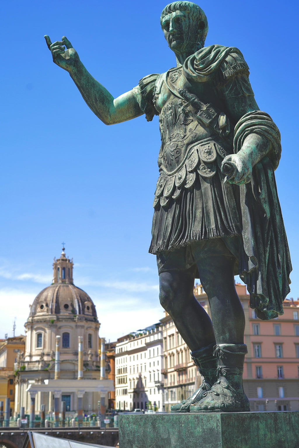 Bronze statue of a roman emperor against a blue sky.